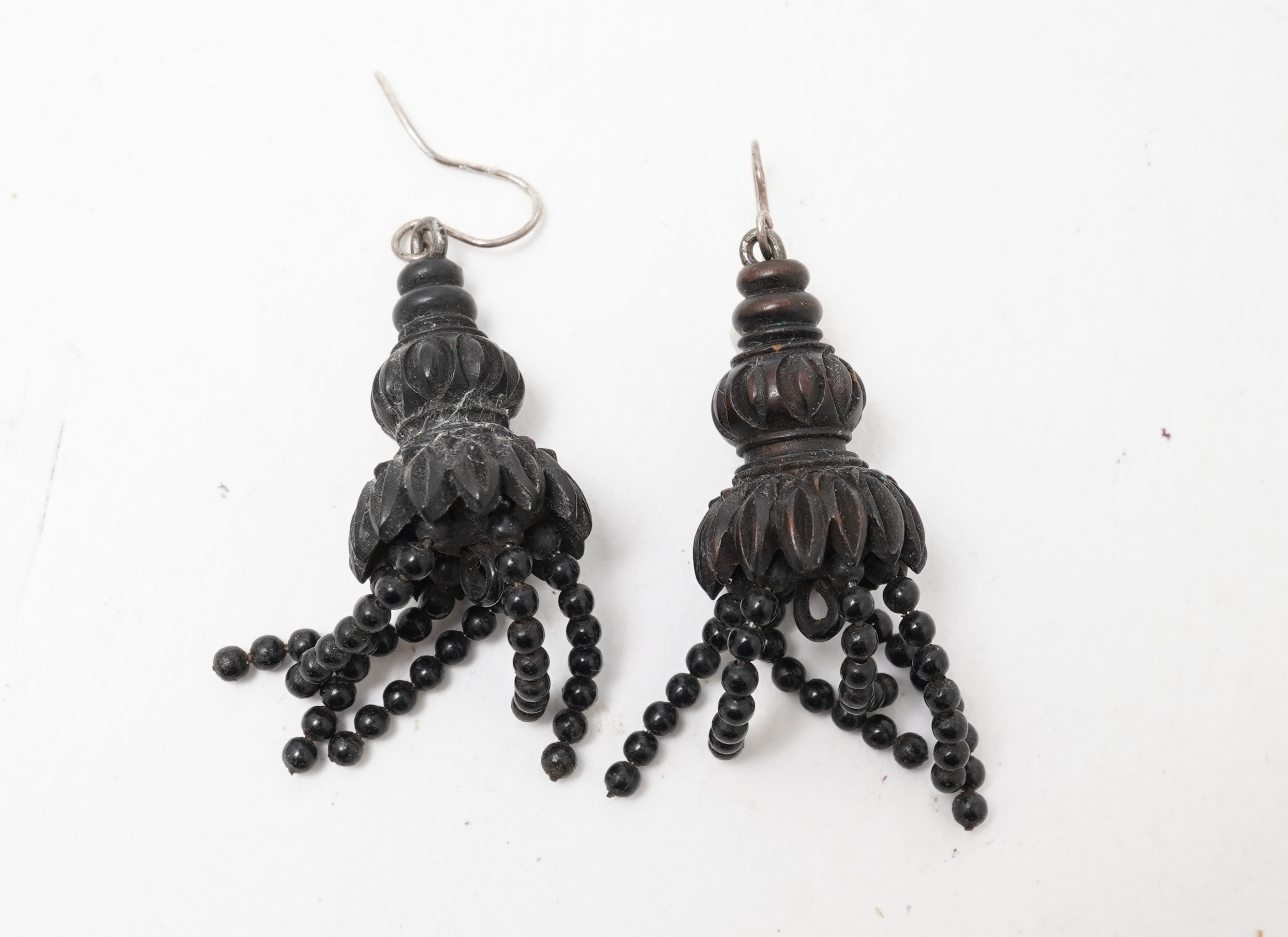 A collection of jewels, comprising: a moulded bog oak brooch depicting a hand holding a posy, length 7.4cm; a carved jet brooch depicting a Gothic ruin, possibly part of Whitby Abbey; a necklace composed of polished pane